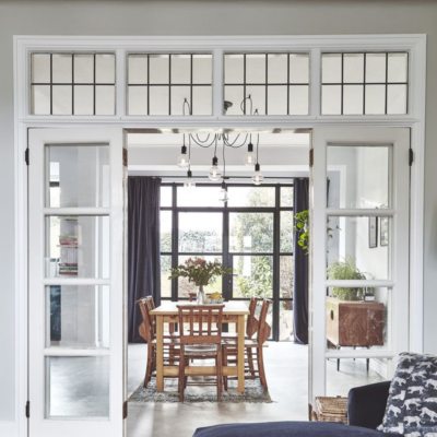 Living room entryway to dining room divided by large white door with windows and transom windows on top