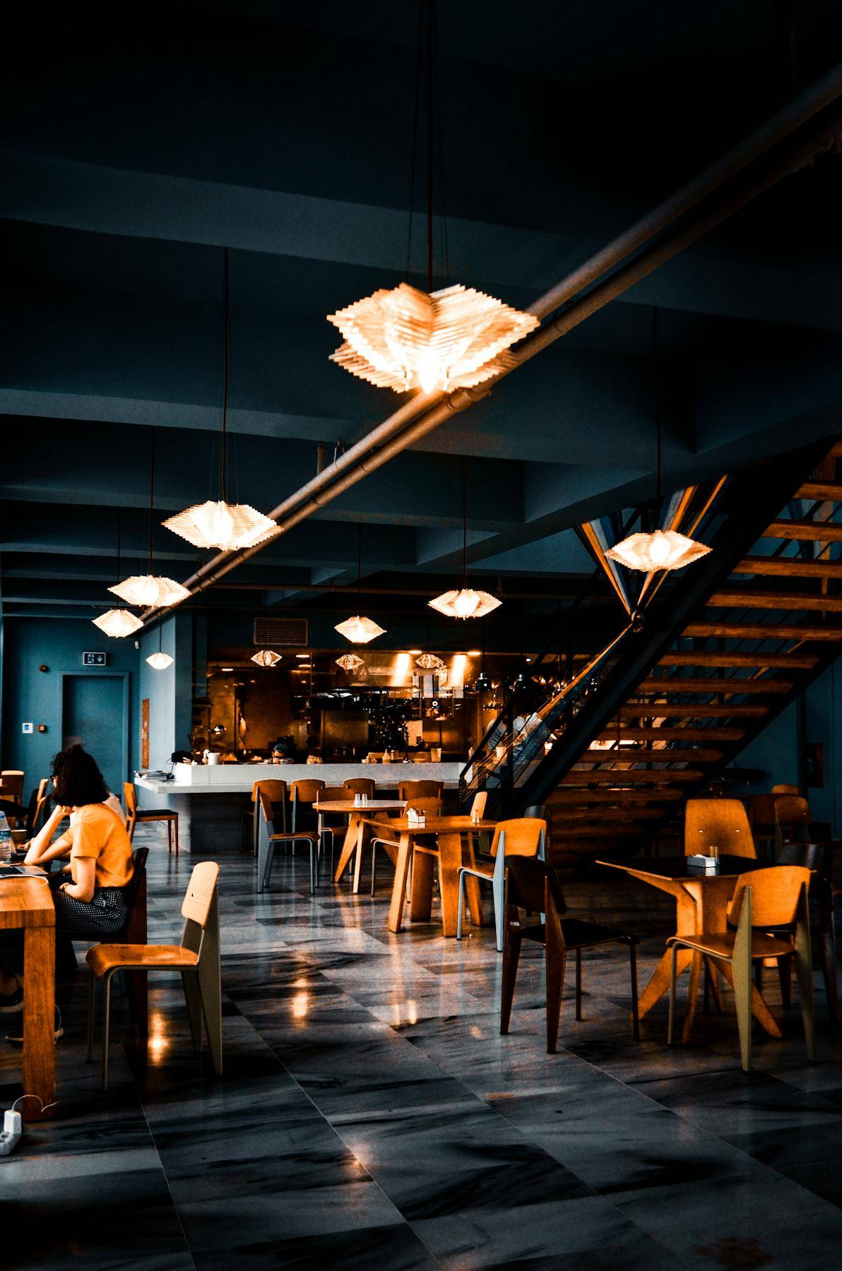 Trendy interior of cafe with creative lamps and wooden furniture with dark painted walls