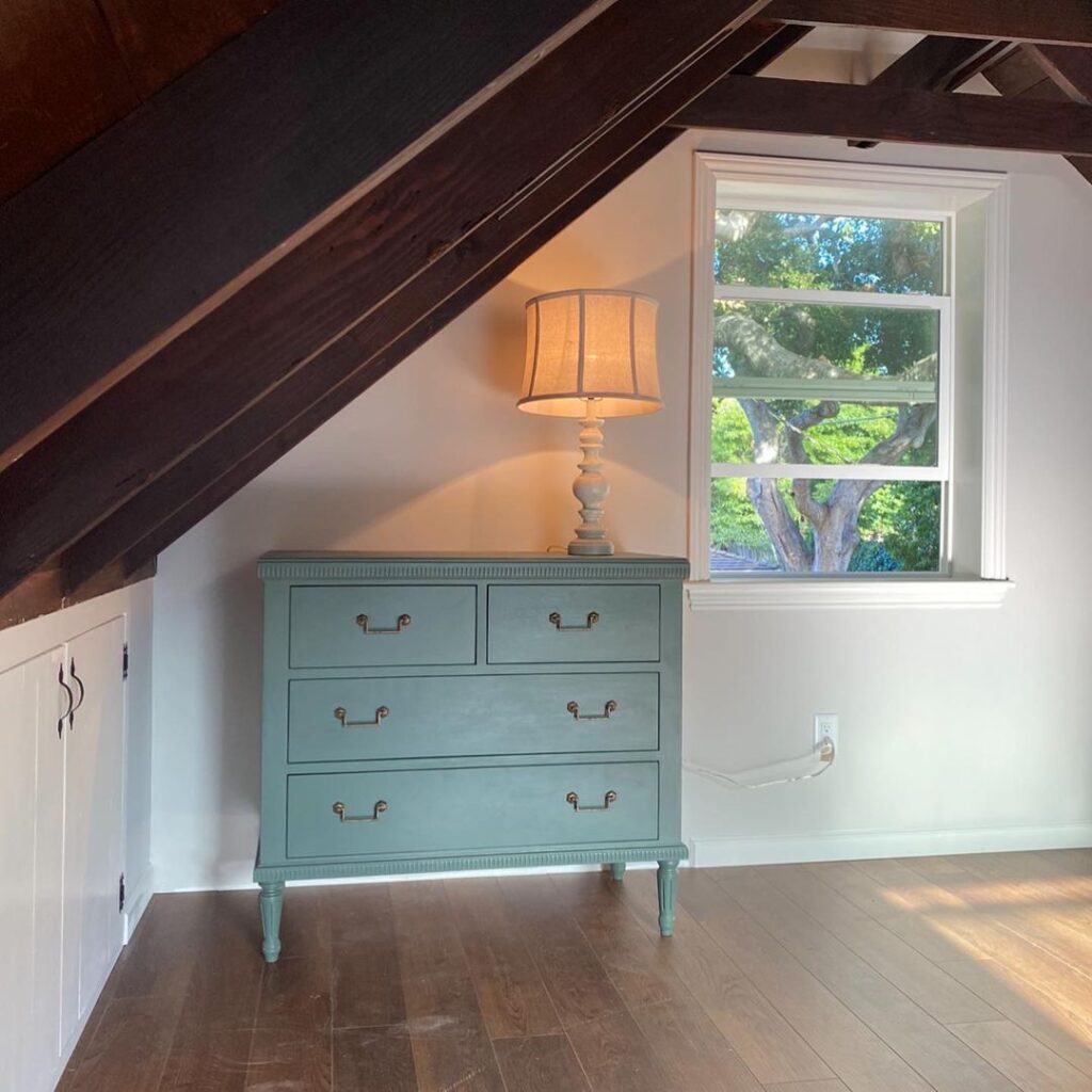 White attic with blue drawers and a white lamp on top of the drawers