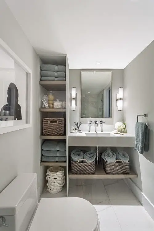 White bathroom with grey towels on shelf and under sink