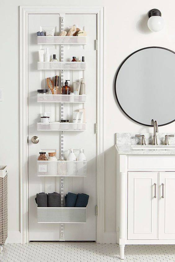 White tiered bathroom organizing shelf hanging on white door