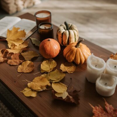 Warm autumn setting with pumpkins, candles, and leaves creating a cozy fall atmosphere.