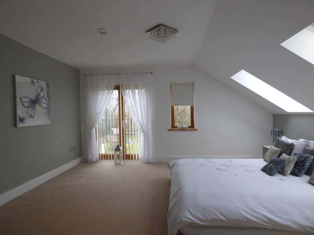 Explore a spacious modern bedroom with skylights, soft decor, and natural lighting.
