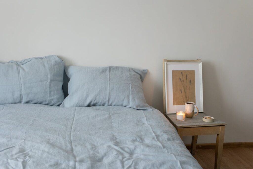 Tranquil bedroom scene featuring a cozy bed, soft linens, and a lighted candle on a wooden side table.