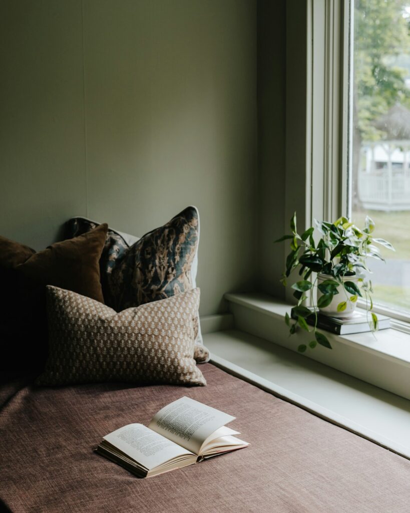 A bed with a book on top of it next to a window